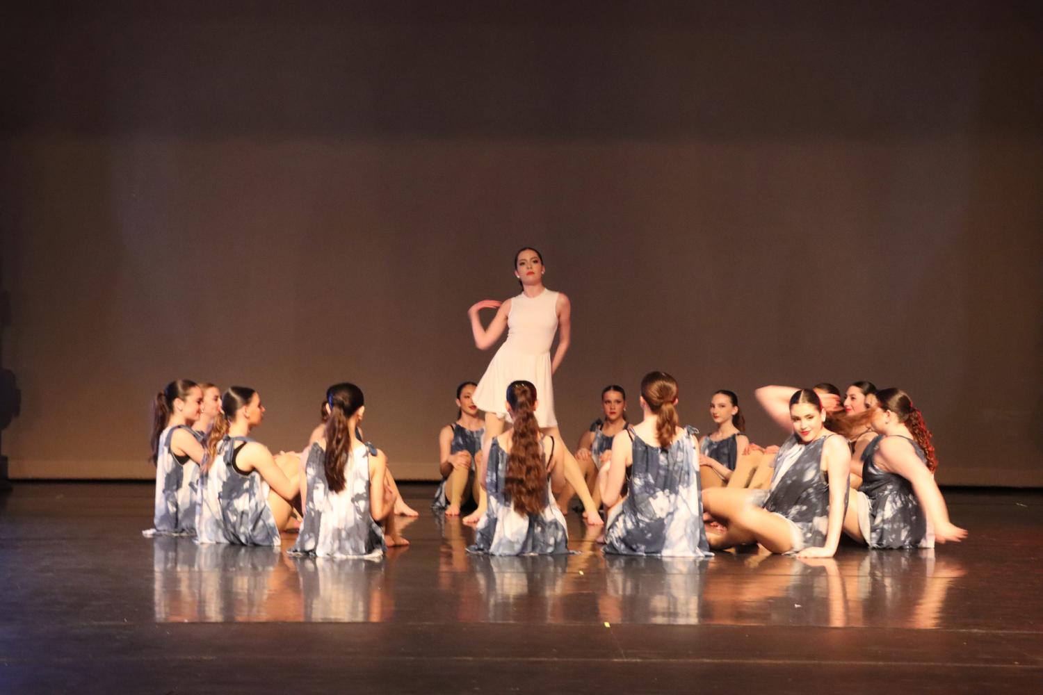 Dancers sitting in a circle with a dancer dressed in white